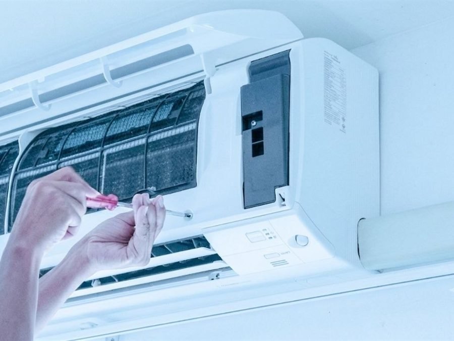 Technicien vissant une unité intérieure de climatisation murale